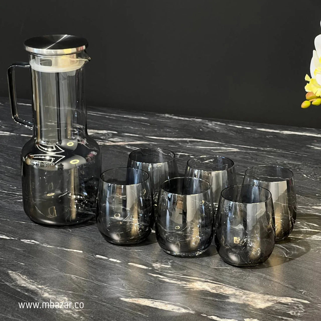 Set of amber glassware including a carafe and three glasses on a beige background