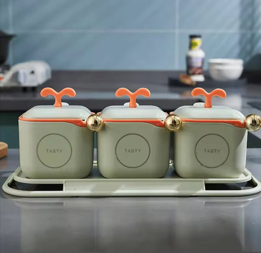 Three green containers with orange lids on a kitchen counter